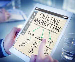  A person interacting with a digital tablet displaying a graphic titled "ONLINE MARKETING", which includes elements such as "S.E.O", "Content", "Lists", and "Sales", represented with checkmarks and arrows